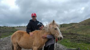 Dois homens estão ao lado de um cavalo castanho. em Refugio Terra Esperanza em Ibarra