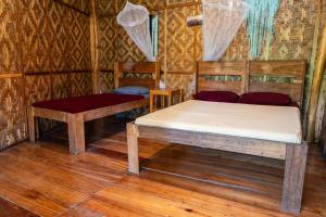 two beds in a room with wooden floors at Soffta Surf Ranch in General Luna