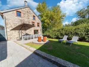 Casa de piedra con 2 sillas y sombrilla en Quaint Holiday Home near Forest in Lierneux en Lierneux