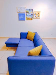 a blue couch with yellow pillows in a room at Fahrenheit Pavillion BY JS HomeStay in Kuala Lumpur