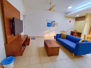 a living room with a blue couch and a tv at Fahrenheit Pavillion BY JS HomeStay in Kuala Lumpur