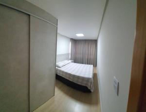 um pequeno quarto com uma cama e um espelho em Delicadeza e aconchego na Serra Gaúcha. em Bento Gonçalves