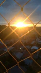 vistas al sol a través de una valla de alambre en Delicadeza e aconchego na Serra Gaúcha., en Bento Gonçalves