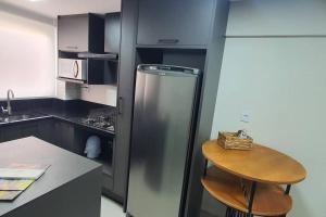 uma cozinha com um frigorífico de aço inoxidável e um banco em Delicadeza e aconchego na Serra Gaúcha. em Bento Gonçalves