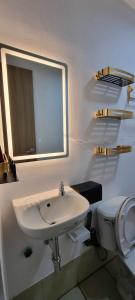 ein Badezimmer mit einem Waschbecken, einem WC und einem Spiegel in der Unterkunft Auberge at SMDC Hope Residences in Trece Martires