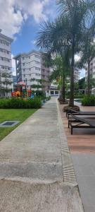 a park with benches and palm trees and buildings at Auberge at SMDC Hope Residences in Trece Martires