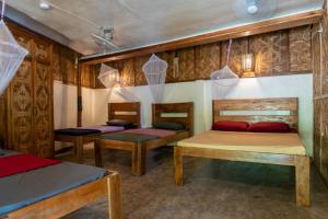 three beds in a room with wooden walls at Soffta Surf Ranch in General Luna