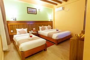 una camera d'albergo con due letti e uno specchio di Paradise Boutique Hotel a Pokhara