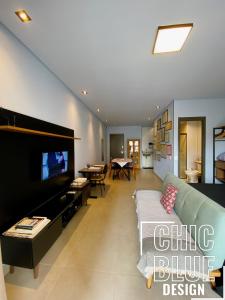 a living room with a couch and a tv at Chic Blue Design com Vaga de Garagem in São Paulo