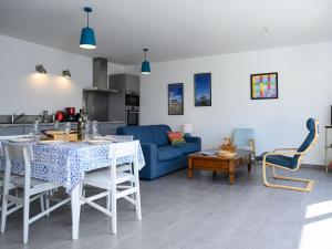 ein Wohnzimmer mit einem Tisch und einem blauen Sofa in der Unterkunft Maison moderne près plage Aiguillon - 2 chambres, terrasse, jardin, parking - Calme et confort - FR-1-420-63 in Arcachon
