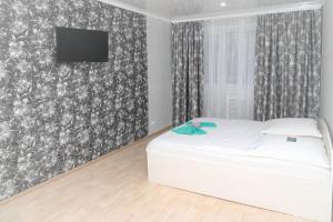 1 dormitorio con cama blanca y TV en la pared en Хельсенки, en Petropavlovsk