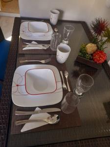 una mesa con platos blancos y rojos y cubiertos en ESTUDIO 21, en Barra de Navidad