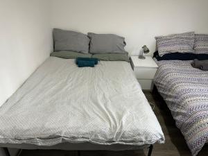 a bedroom with two beds and a white wall at Wembley Homes Serviced Apartment, 25mins to Central London in Wembley