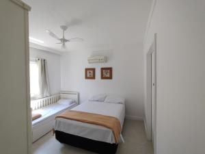 a white bedroom with a bed and a window at Casa Sol Nascente in Cabo Frio