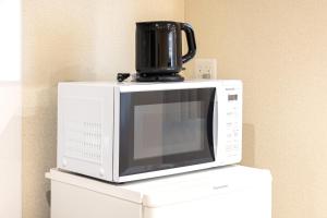 a microwave with a coffee pot on top of it at Grace Hotel Kyodo odakyu line near shinjuku shibuya in Tokyo