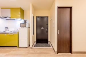 a kitchen with a door and a refrigerator at Grace Hotel Kyodo odakyu line near shinjuku shibuya in Tokyo
