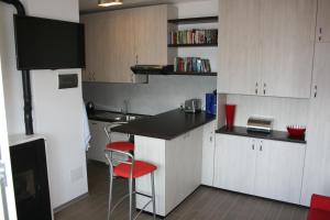 a kitchen with white cabinets and a counter with red chairs at Apartment Imma in Tremosine Sul Garda