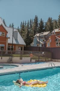 a woman laying on a surfboard in a swimming pool at Ski-in/Ski-out Intentionally Designed Ski Lodge in Whistler