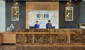 順化的住宿－KOBI Onsen Resort Hue，两名男子站在带笔记本电脑的前台