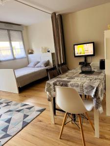 a room with a table and a bed and a television at Appartement Disneyland Paris Val d'Europe La vallée Village parking 500m gare Val d'Europe in Montévrain