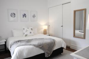 a white bedroom with a bed and a mirror at Yallingup Homestead Guest House in Dunsborough