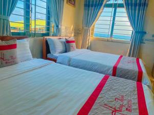 two beds in a room with two windows at KHÁCH SẠN HƯNG THỊNH - Lý Sơn in Ly Son