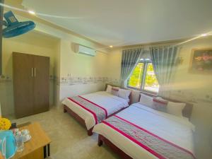 um quarto com 2 camas, uma mesa e uma janela em KHÁCH SẠN HƯNG THỊNH - Lý Sơn em Ly Son