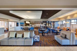 a lobby of a hotel with a couch and tables and chairs at Courtyard Detroit Southfield in Southfield