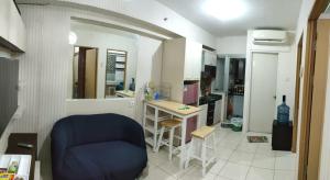 ein Wohnzimmer mit einem blauen Stuhl und eine Küche in der Unterkunft Apartemen Pakuwon Educity yale in Surabaya