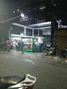 um grupo de pessoas em pé fora de um mercado à noite em Como en Casa em Caracas