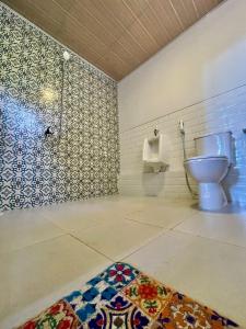 a bathroom with a toilet and a urinal and a rug at Omah Alchy Cottages in Karimunjawa