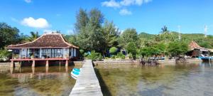 a building on the water with a dock in the water at Omah Alchy Cottages in Karimunjawa