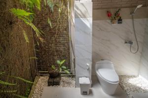 ein Badezimmer mit WC und eine Wand mit Pflanzen in der Unterkunft Puri Bayu in Ubud