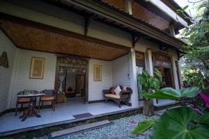 une terrasse couverte d'une maison avec une table et des chaises dans l'établissement Puri Bayu, à Ubud