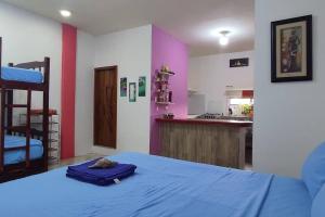 a bedroom with a blue bed and a kitchen at Tortuga House in Puerto Baquerizo Moreno