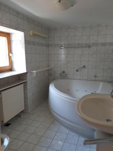 La salle de bains blanche est pourvue d'une baignoire et d'un lavabo. dans l'établissement Riederhof, à Flintsbach am Inn