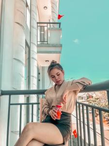 een vrouw op een balkon met een drankje bij KHÁCH SẠN HƯNG THỊNH - Lý Sơn in Ly Son