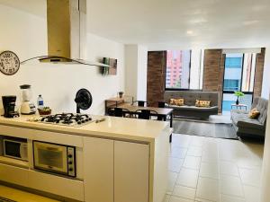 a kitchen with a stove and a living room at Apartamento Lauret en Laureles in Medellín