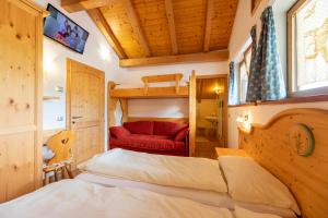 1 dormitorio con 1 cama y 1 sofá rojo en B.& B. Corradini en Castello di Fiemme