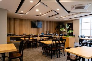 a restaurant with tables and chairs and a flat screen tv at Arcadia Hotel Manado in Manado