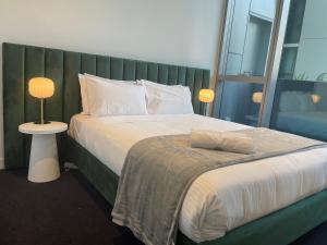 Schlafzimmer mit einem großen Bett mit einem grünen Kopfteil in der Unterkunft Superior 3 Bedroom 2 Bathroom Apt Melbourne CBD in Melbourne