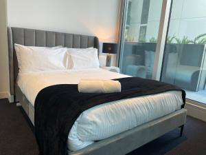 ein Schlafzimmer mit einem großen Bett und einem großen Fenster in der Unterkunft Superior 3 Bedroom 2 Bathroom Apt Melbourne CBD in Melbourne