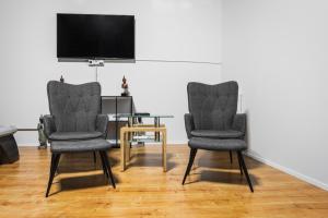 2 Stühle und ein Tisch mit einem TV in einem Zimmer in der Unterkunft Wellness Apartman Vrakuna in Bratislava