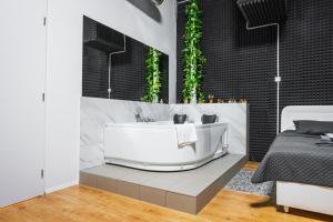 ein Bad mit einer weißen Badewanne und einem Bett in der Unterkunft Wellness Apartman Vrakuna in Bratislava