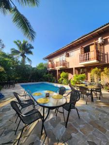 un patio con mesas y sillas junto a una piscina en Pousada Dois Irmãos en Trindade