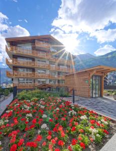 un bâtiment avec un jardin fleuri devant lui dans l'établissement Naco Aparthotel, by Arca Solebad, à Zermatt