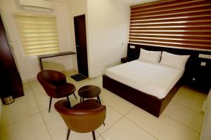 a hotel room with a bed and a chair at Arctic Business Hotel in Cochin