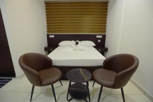 a bedroom with a bed and two chairs at Arctic Business Hotel in Cochin