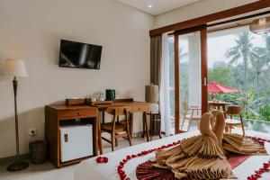 a bedroom with a bed with a desk and a television at Sanubari Ubud in Ubud