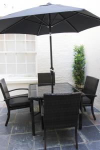 una mesa y sillas con una sombrilla en el patio en Paddington Patio Apartment en Londres